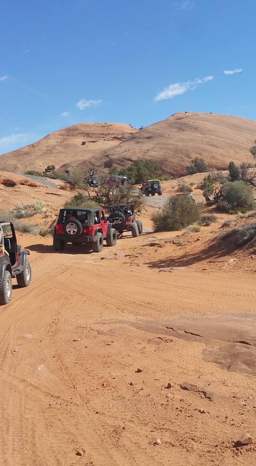Off-road Jeeps driving on a sandy desert trail.