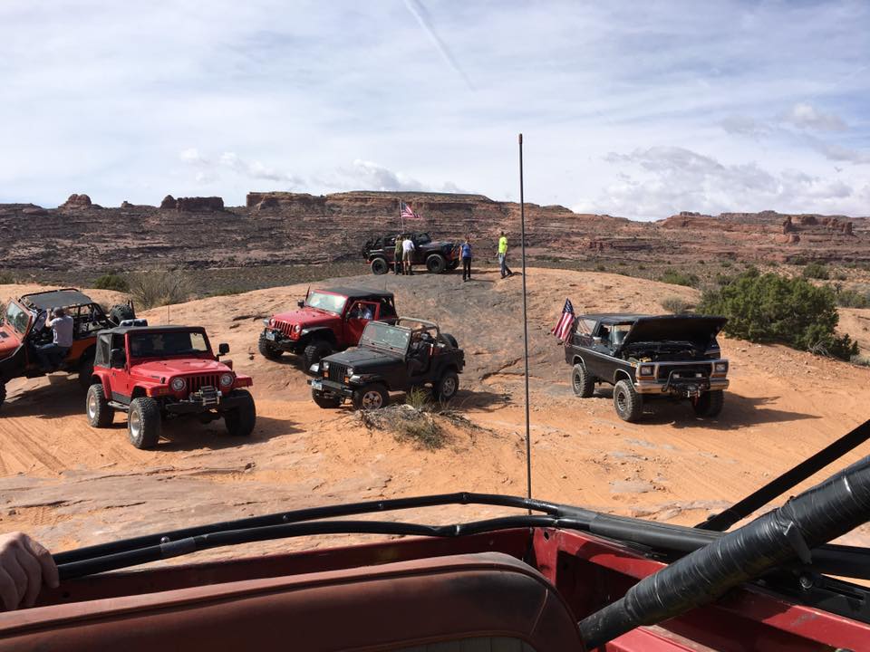 Several off-road vehicles including Jeeps and a Ford Bronco on a desert trail.