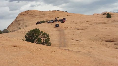 1979 Ford Bronco - Several off-road vehicles, including Jeeps, navigate a rocky, desert landscape under a cloudy sky. One Jeep is prominently featured driving…