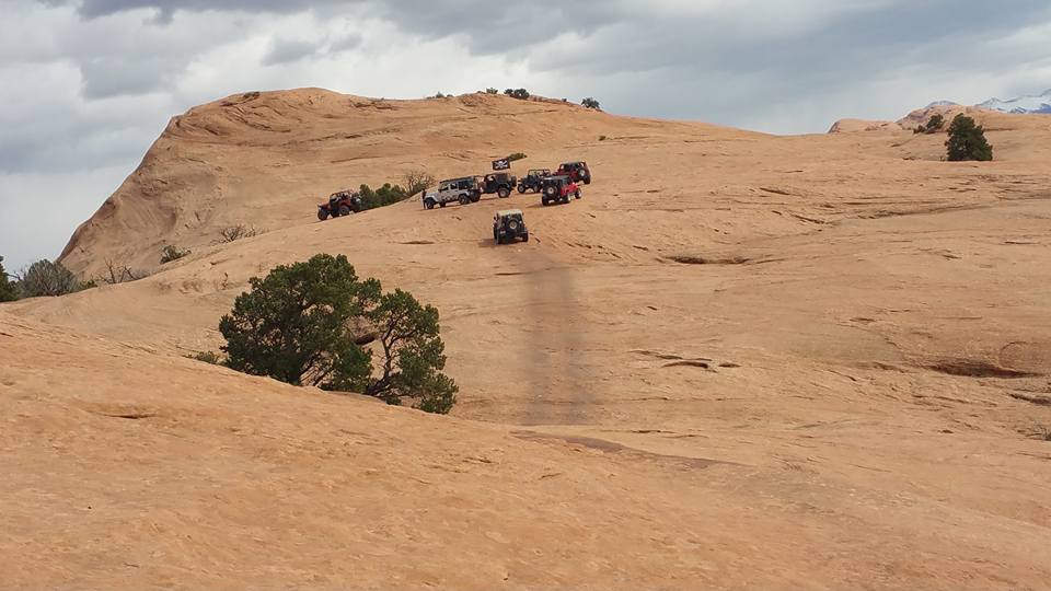 Off-road Jeeps driving on a rocky desert trail.
