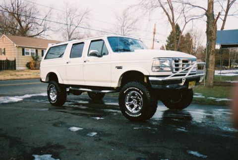 1996 Ford C-250 (Centurion Conversions) - White 1996 Ford C-250 Centurion Conversions SUV parked on wet asphalt.