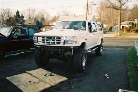 1996 Ford C-250 (Centurion Conversions) - A white SUV with a lifted suspension and large off-road tires is parked in a driveway.