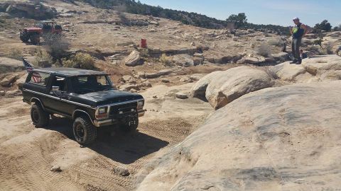 1979 Ford Bronco - A black 1979 Ford Bronco is parked on a dusty, rocky trail with an American flag visible in the rear window. Another off-road vehicle is vi…