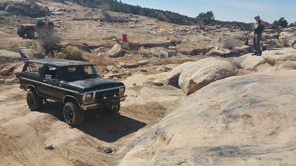 Black 1979 Ford Bronco on a rocky off-road trail with an American flag.