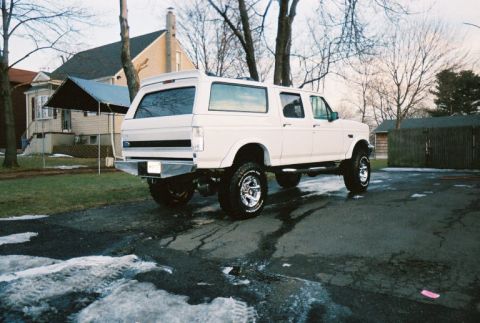 1996 Ford C-250 (Centurion Conversions) - This lifted white SUV is parked in a driveway with a house and trees in the background.