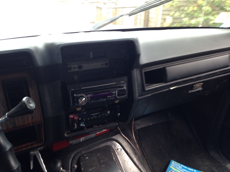 Interior dashboard of a vehicle with two car stereos, gear shifter, and steering wheel.