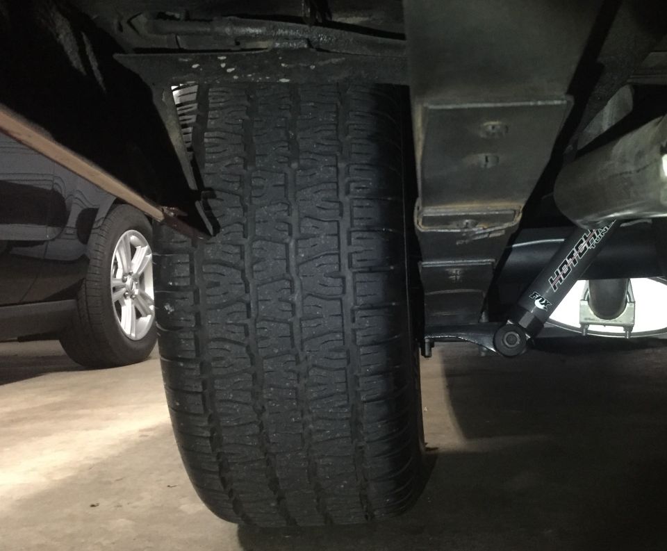 Rear suspension of a vehicle with tire, leaf springs, and a FOX shock absorber.
