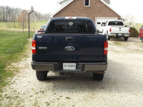 2005 Ford F-150 - A dark blue Ford F-150 is parked in a driveway with a white truck behind it.