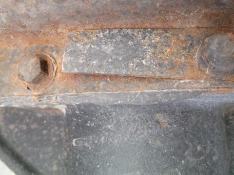 2005 Ford F-150 - A close-up view of heavily rusted metal components, including a bolt, with some black material visible.