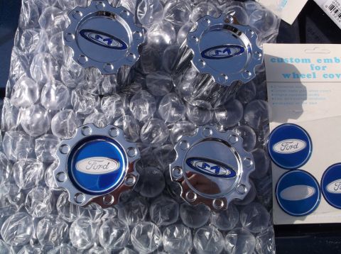2005 Ford F-150 - Set of four Ford F-150 wheel center caps, two showing the Ford emblem and two with an 'M' logo.