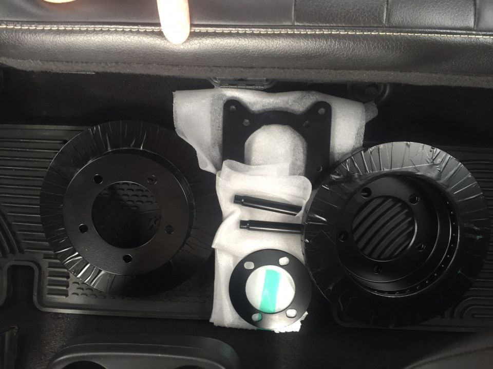 new brake rotors and mounting hardware laid out on a black mat