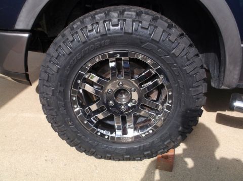 2005 Ford F-150 - A close-up view of a custom chrome wheel and aggressive off-road tire mounted on a truck.