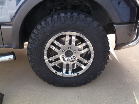 2005 Ford F-150 - Close-up of a chrome wheel and aggressive off-road tire mounted on the side of a dark-colored truck.