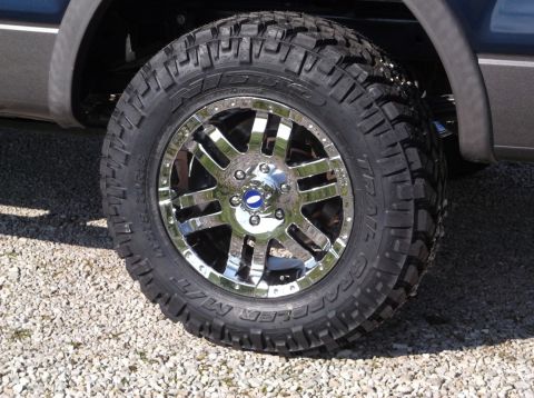 2005 Ford F-150 - A close-up of a custom chrome wheel and aggressive off-road tire mounted on a truck.