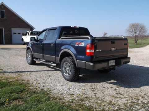 2005 Ford F-150 - Blue 2005 Ford F-150 FX4 pickup truck with aftermarket wheels and tires is parked outside a garage.