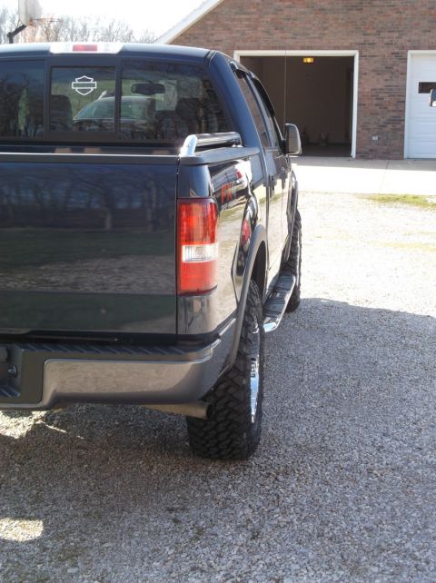 2005 Ford F-150 - Rear view of a dark pickup truck, possibly a 2005 Ford F-150, showing its wheel and tire assembly.