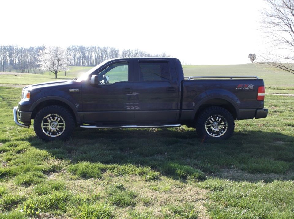 Dark blue Ford F-150 pickup truck parked on grass. Has 4x4 OFF ROAD decal on the rear fender