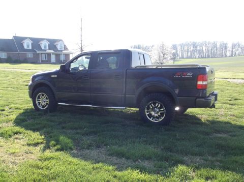 2005 Ford F-150 - Dark blue Ford F-150 truck with FX4 Off Road badging is parked on a grassy field near a house.