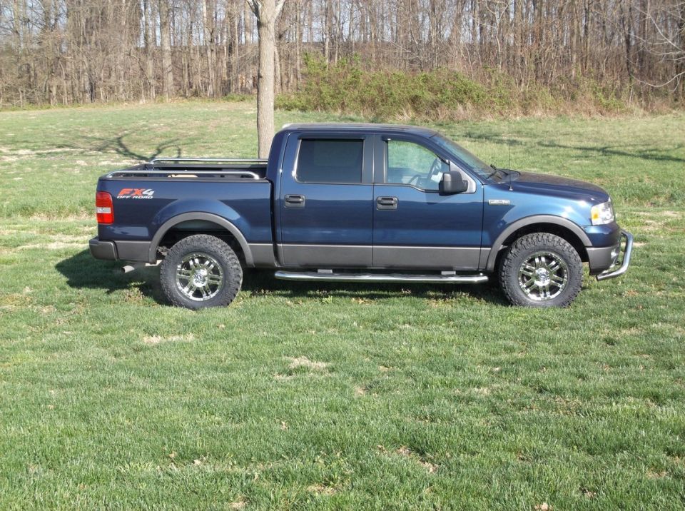 Blue Ford F-150 pickup truck, side view, with aftermarket wheels and tires