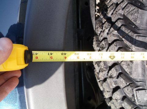 2005 Ford F-150 - A tape measure is used to check the clearance between a vehicle's fender and a large off-road tire.
