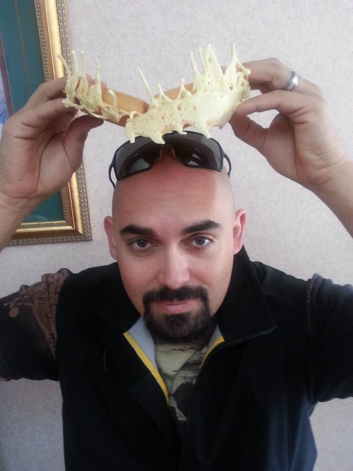 Man with goatee and sunglasses on his head wears a fried dough creation as a crown