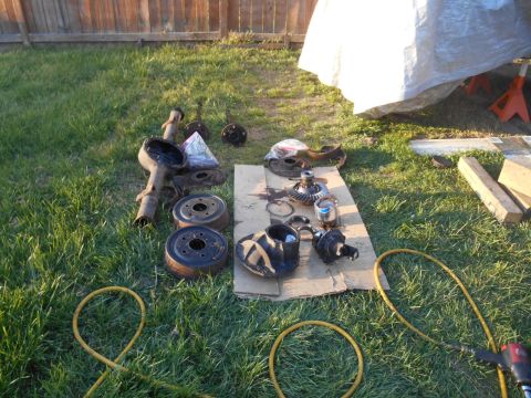 1972 Ford Bronco - Various vehicle axle and differential components are spread out on the lawn for restoration work.