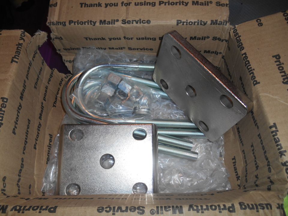 Metal U-bolts, nuts, and square mounting plates inside a Priority Mail box