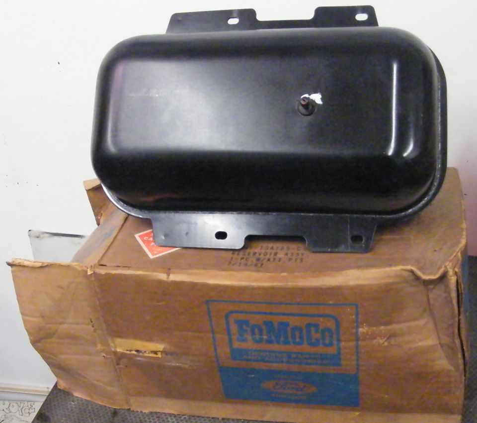 Black metal reservoir with mounting brackets sits on a FoMoCo branded cardboard box
