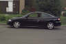 1994 Ford Taurus - Side profile of a black coupe, likely a 1995 Chevrolet Cavalier, parked curbside.