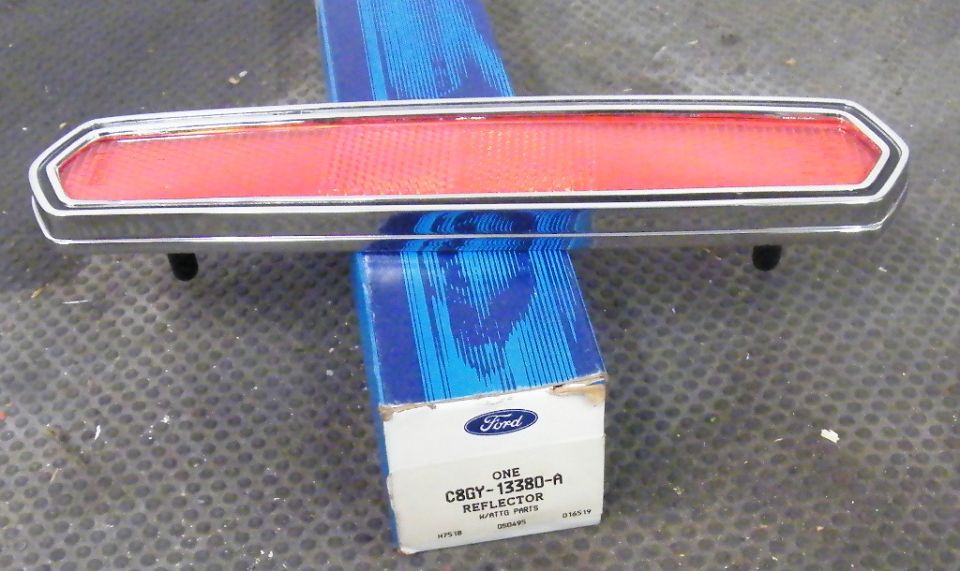 Red car reflector with chrome trim on a Ford parts box