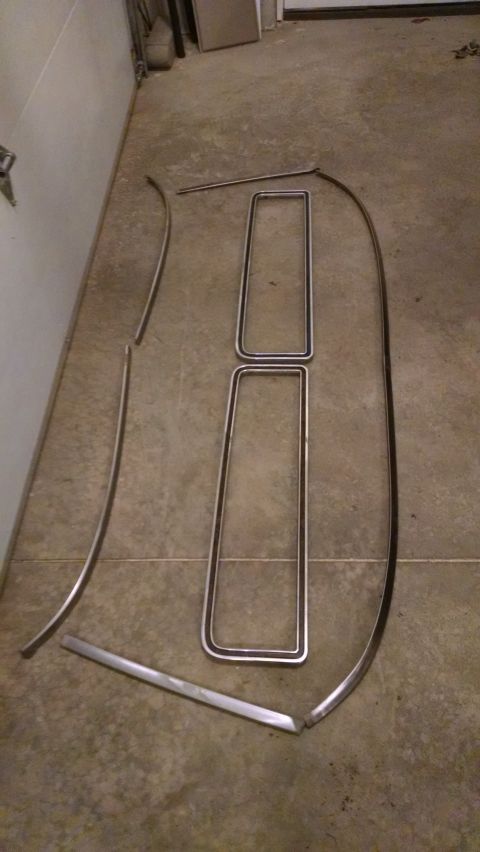 1979 Ford F-150 - Several chrome trim pieces are arranged on a concrete floor, possibly for a vehicle restoration project.