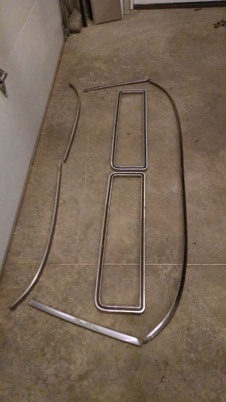 chrome trim pieces laid out on a garage floor