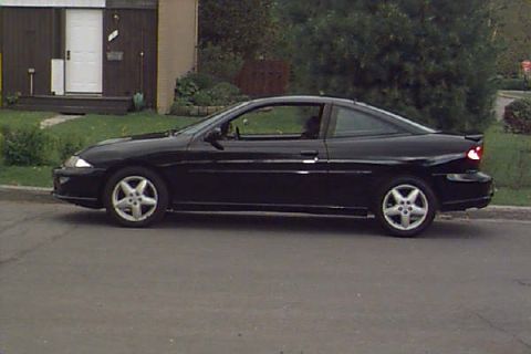 1994 Ford Taurus - Side view of a black coupe parked on a street in front of a house.