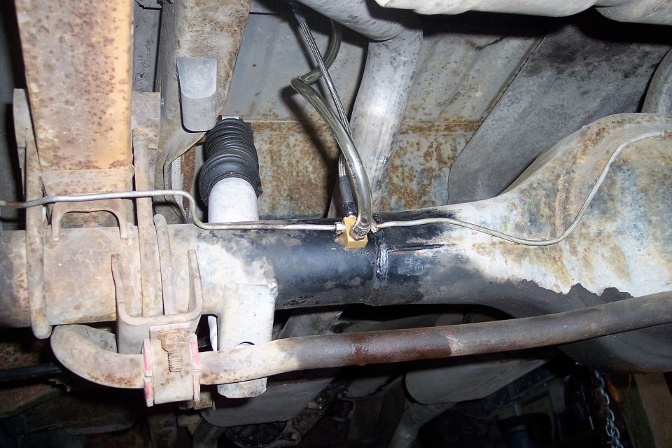 Underside view of a vehicle's rear axle showing brake lines and a shock absorber