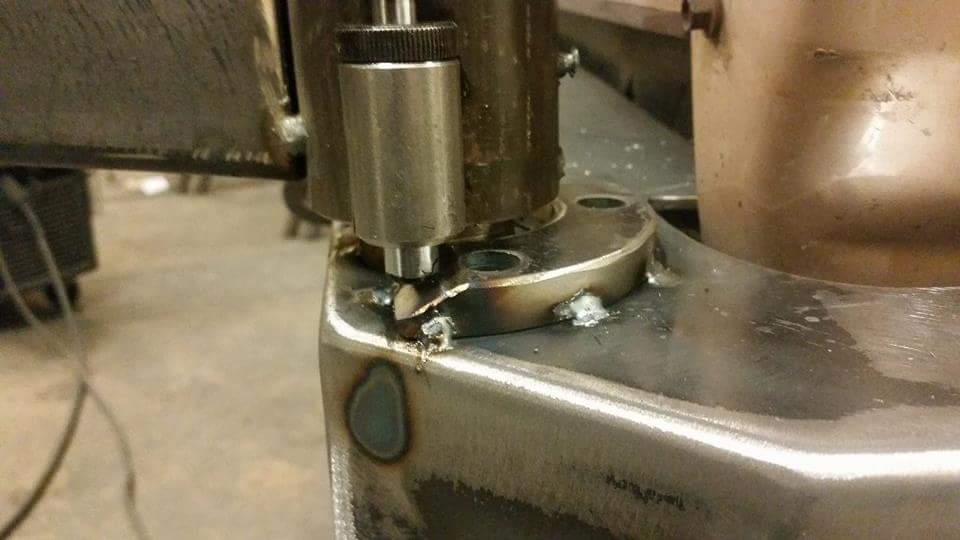 Close-up of metal fabrication on a vehicle frame, showing welds and a mechanical component