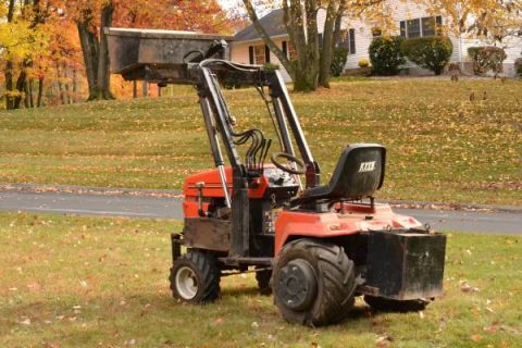 1982 Kubota RTV900 - Tractor with front loader sits on a grassy lawn during autumn. The seat has a 'KEE' logo.