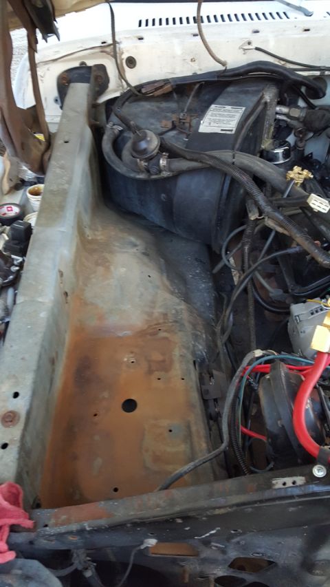 1978 Ford Bronco - The engine bay of a classic Ford Bronco shows the firewall, heater box, and wiring harness. Rust is visible on the metal components.