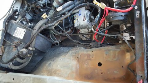 1978 Ford Bronco - A close-up view of the engine bay of a 1978 Ford Bronco, showing the alternator, hoses, and wiring. The metal frame beneath the engine show…