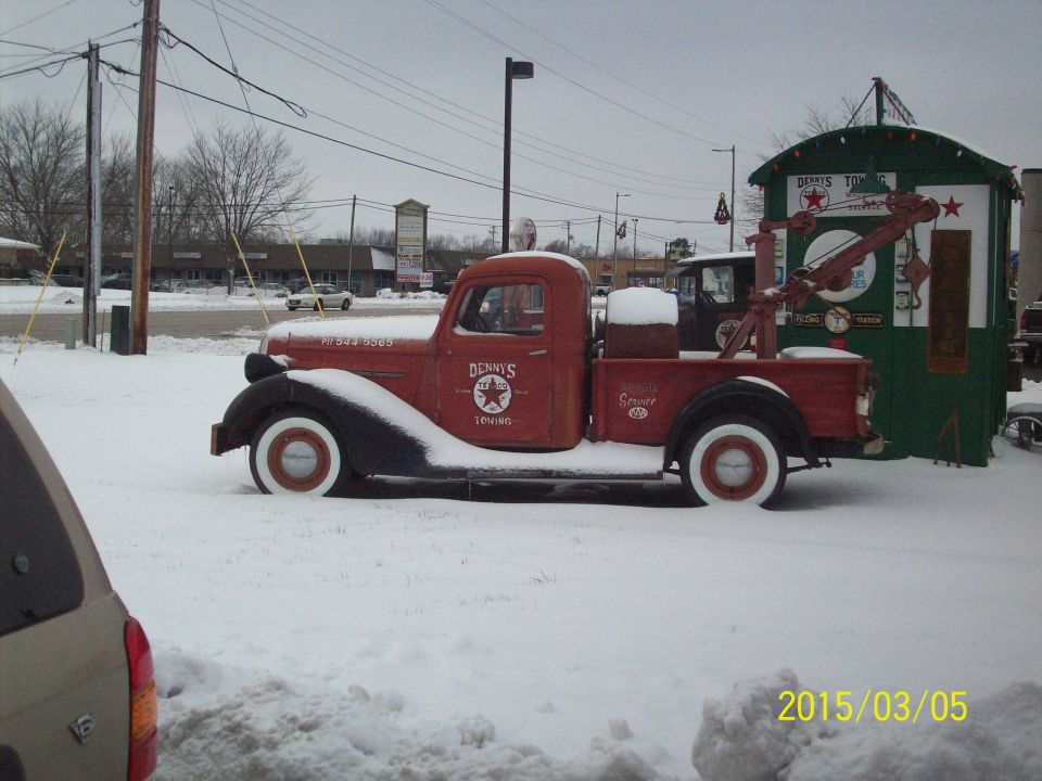 Vintage red tow truck with Denny's Towing logo in the snow.