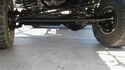1979 Ford Bronco - The underside of a lifted 4x4 vehicle shows a heavy-duty steering system and differential housing. The front suspension components, includi…