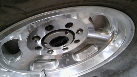 1979 Ford Bronco - A close-up, slightly angled shot shows the front wheel hub and part of the tire of a vehicle. The hub has a silver finish with black accent…