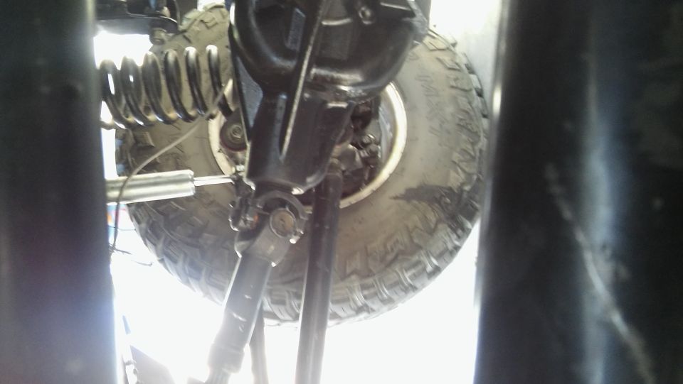 Underside of a vehicle showing rear axle, suspension, tire, and driveshaft.