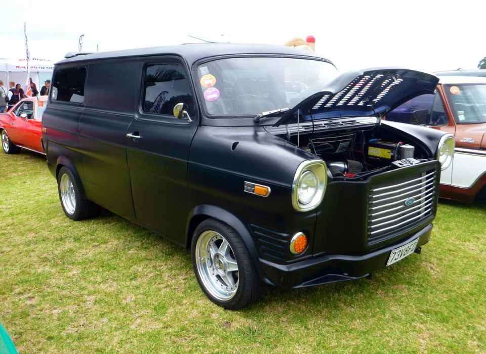 Matte black panel van with hood open, chrome grille, and aftermarket wheels.