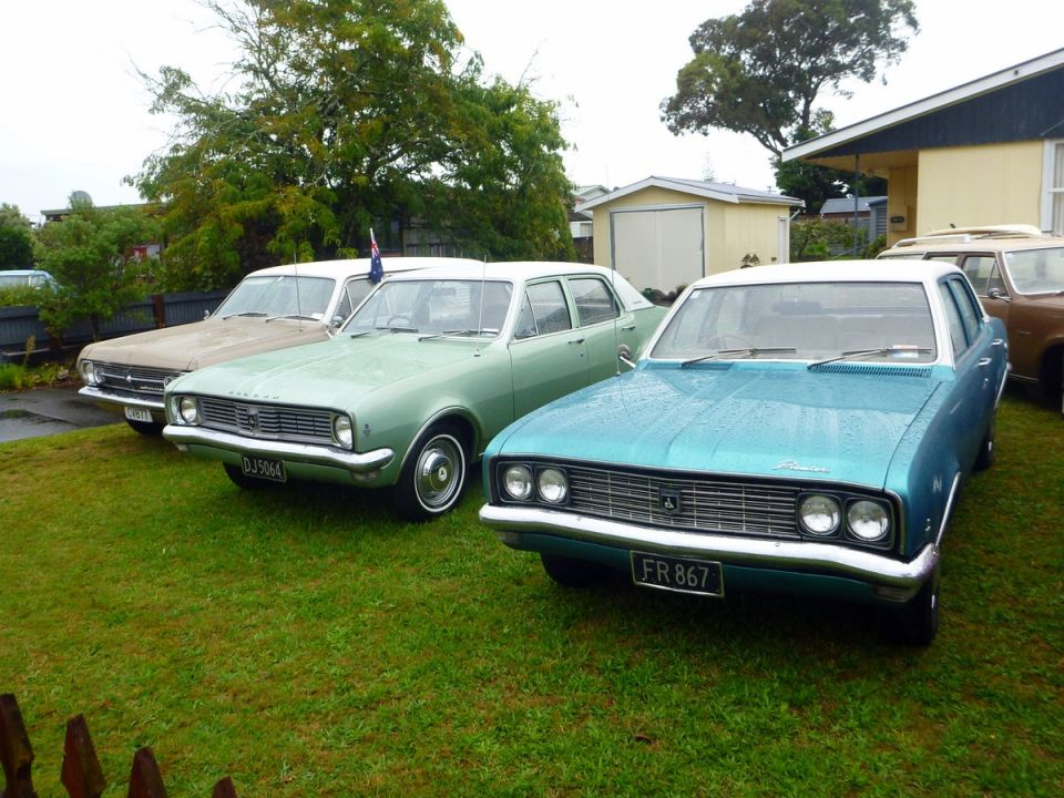 Teal and green classic sedans parked on grass.