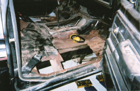 1978 Ford Bronco - The interior of a vehicle shows significant rust damage and is in a state of disassembly.