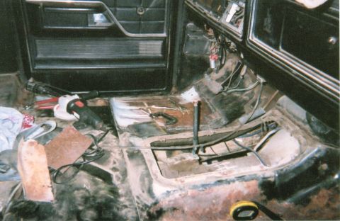 1978 Ford Bronco - The interior of a vehicle shows significant rust on the floor and is cluttered with tools, suggesting a restoration project is underway.