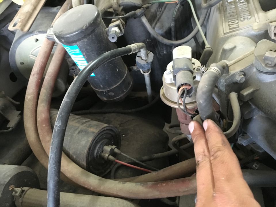 Engine bay of a 1987 Ford Bronco showing hoses, filter, and sensor.