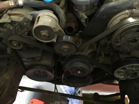 1987 Ford Bronco - A close-up view of the serpentine belt system on a Ford Bronco engine, showing the alternator, tensioner pulley, and various other pulleys.