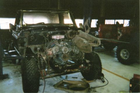 1978 Ford Bronco - A black 1978 Ford Bronco is disassembled and lifted in a garage, with another vehicle visible in the background.