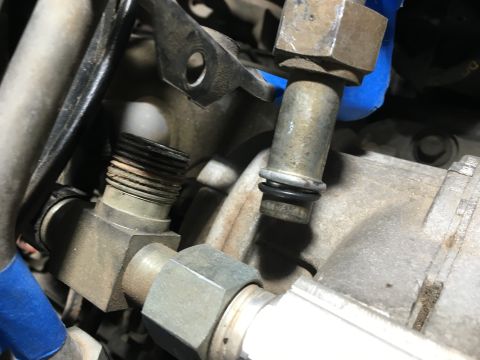 1987 Ford Bronco - Close-up view of metal fuel line fittings and O-rings on a vehicle engine. One fitting has visible threads, while another has a black O-rin…